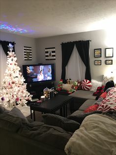 a living room filled with furniture and a christmas tree in front of a tv set