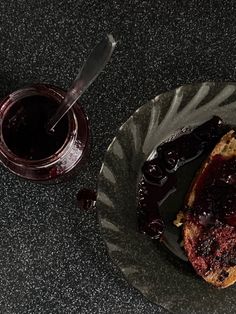 a piece of bread with jam on it next to a cup of coffee and spoon