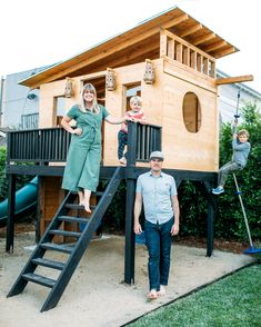 two children and an adult standing in front of a tree house