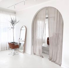 an arched window with sheer curtains in a white room