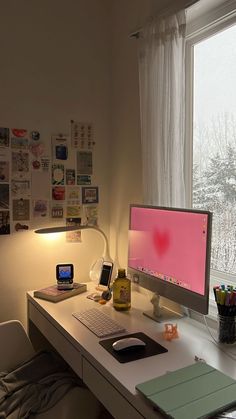 a desk with a computer monitor, keyboard and mouse on it in front of a window