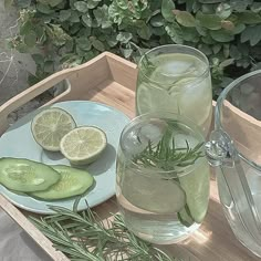 a tray with two glasses and some sliced cucumbers on it next to a pitcher of water