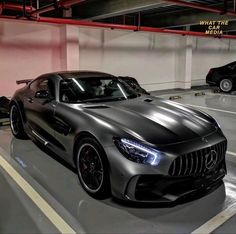 two cars parked in a parking garage next to each other on the floor and one is black