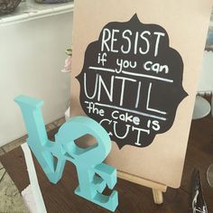 a sign that reads resist if you can until the cake is cut on it next to a small sculpture