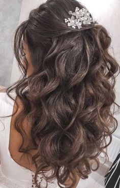 the back of a woman's head with wavy hair and flowers in her hair