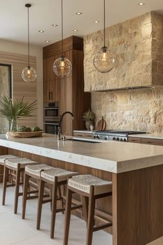 a kitchen island with stools and lights hanging from it's ceiling over the counter