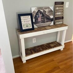 a white table with two pictures on top and a framed picture next to it in front of a gray wall