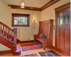 an entryway with wooden stairs and wood paneling, along with a rug on the floor