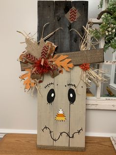 a wooden block with a scarecrow face on it's side and some leaves sticking out of the top