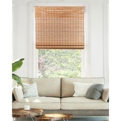 a living room with a couch, coffee table and bamboo shades on the window sill