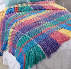 a multicolored crocheted blanket on a bed with white sheets and pillows