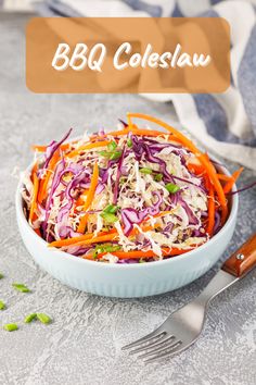 a white bowl filled with coleslaw and carrots next to a silver fork