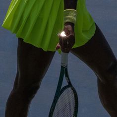 a woman holding a tennis racquet on top of a tennis court with her leg