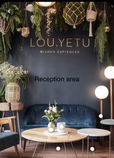 a living room with blue couches and plants on the wall behind it, in front of a sign that says louuyetu