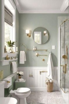 a white bathroom with green walls and gold fixtures on the vanity, toilet and shower