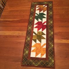 a long table runner with an arrow design on the bottom and green, red, yellow and orange strips across it