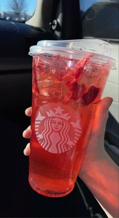 a person holding up a starbucks drink with strawberries on the rim in their hand