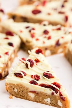 several pieces of cake with white frosting and cranberry toppings on top