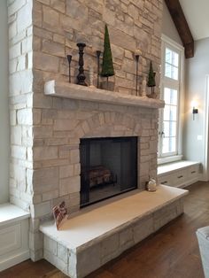 a living room with a stone fireplace and windows