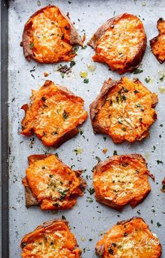 baked sweet potatoes with parmesan cheese and herbs arranged on a baking sheet, ready to be eaten