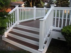 a wooden deck with white railing and steps