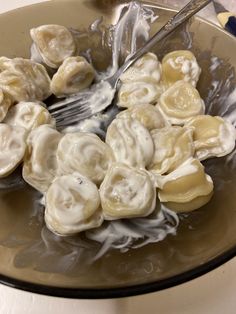 a bowl filled with dumplings and sauce on top of a table