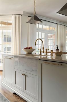 a kitchen with marble counter tops and gold faucet lighting over the stovetop