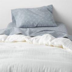 an unmade bed with white sheets and blue polka dot pillow cases on the headboard