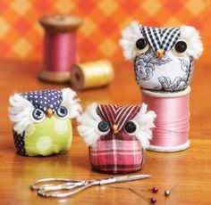 three owls made out of fabric sitting next to spools of thread