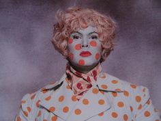 a woman with orange polka dots painted on her face and hair is posing for the camera