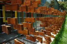 a fence made out of wood blocks on the side of a building with grass growing next to it