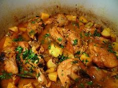 a pot filled with meat and vegetables covered in gravy, garnished with parsley