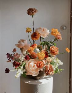 a white cake topped with lots of different colored flowers on top of a wooden table