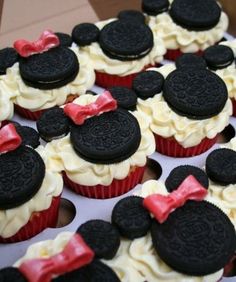 cupcakes with white frosting and red bows are decorated in mickey mouse ears