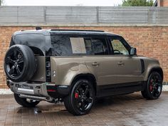 an suv is parked in front of a brick wall with black rims on it