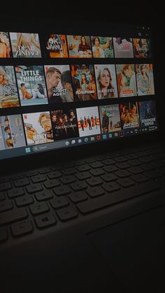 an open laptop computer sitting on top of a desk with many movies on the screen