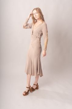 Stunningly preserved 1920’s mauve & ecru bias cut dress with attached jacket, lace trim, and asymmetrical cut. Best fits modern size S-M Length 52”Pit to pit 18.5”Waist 26-30”Hips 31-42” Model’s Measurements:Height 5’9”Chest 34”Waist 29”Hips 36.5” Excellent vintage condition, with normal wear and condition for its age.For international shipping rates, please send inquiries to our CONTACT page. Fitted Lace Trim Midi Dress For Fall, Fitted Bias Cut Dresses For Fall, Cream Fitted Midi Dress With Lace Trim, Fitted Cream Midi Dress With Lace Trim, Fitted Bias Cut Midi Dress For Daywear, Fitted Long Sleeve Bias Cut Midi Dress, Taupe Fitted V-neck Dress, Daywear Fitted Bias Cut Dresses, Fitted Bias Cut Dresses For Daywear