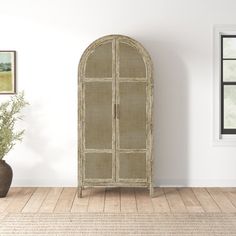 a room with a white wall and a brown cabinet next to a potted plant