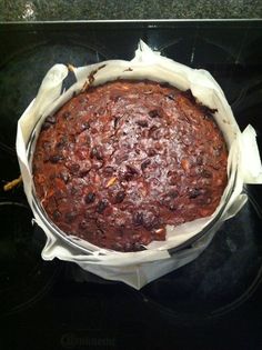 a chocolate cake sitting on top of a stove covered in wax paper and plastic wrap