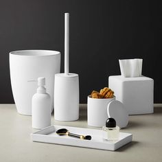 white bathroom accessories including soap dispenser, toothbrush holder and other items