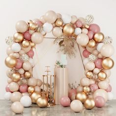 a large balloon arch with gold, white and pink balloons