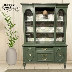 a green china cabinet next to a potted plant on the floor and a happy creations sign above it