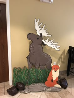 a paper cut out of a moose and a fox sitting on the ground next to each other