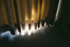 the sun is shining through some curtains on a window sill in a dark room