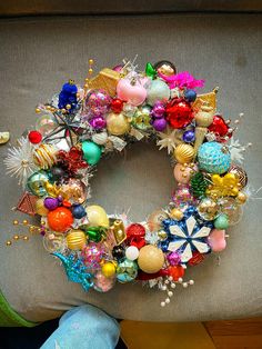 a christmas wreath sitting on top of a couch next to a stuffed animal and other decorations