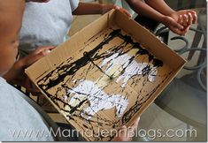 two children are playing with an art project in a box that looks like it has been painted