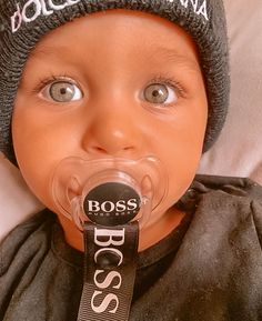 a baby with a pacifier in his mouth wearing a beanie hat and scarf