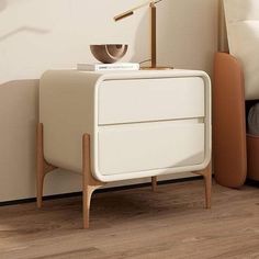 a white nightstand sitting next to a bed on top of a hard wood flooring