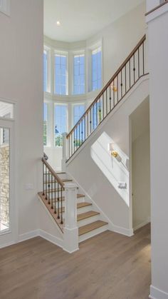 an empty room with white walls and wood floors, stairs leading up to the second floor