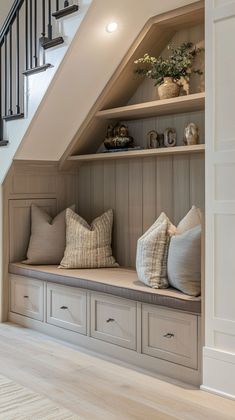 a wooden bench with pillows on it under a stair case